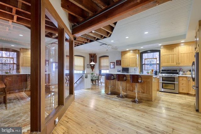 kitchen featuring ceiling fan, light wood-type flooring, range with two ovens, and kitchen peninsula