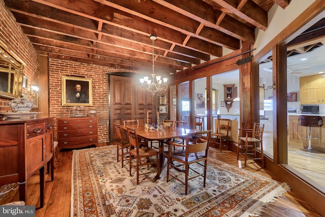 dining space featuring a notable chandelier, hardwood / wood-style floors, and brick wall