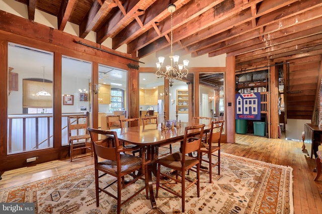 dining area with beamed ceiling, a chandelier, and light hardwood / wood-style floors