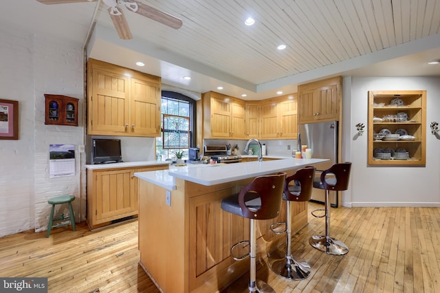 kitchen featuring ceiling fan, a kitchen breakfast bar, a center island with sink, and light hardwood / wood-style floors