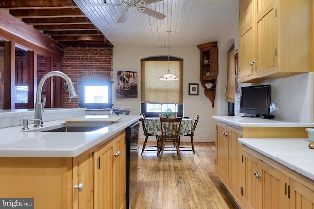 kitchen with light wood-type flooring, ceiling fan, sink, decorative light fixtures, and brick wall