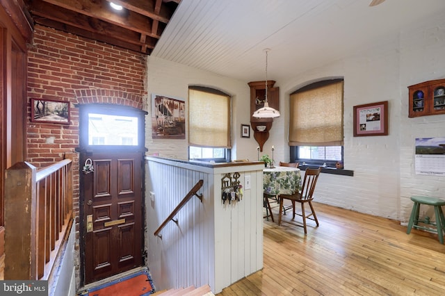 interior space featuring decorative light fixtures, brick wall, and light hardwood / wood-style floors