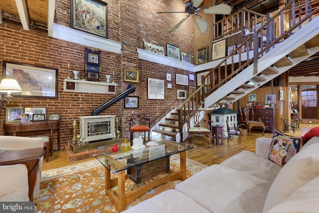 living room featuring brick wall, hardwood / wood-style floors, ceiling fan, and a high ceiling