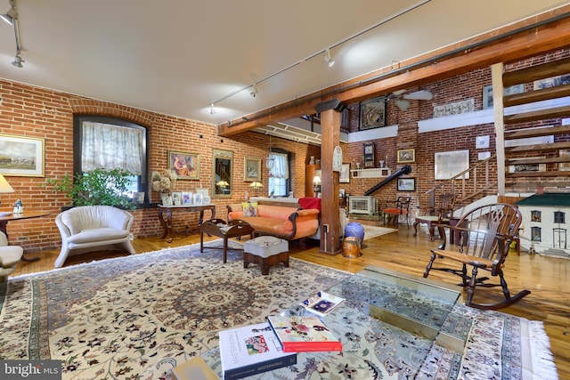 sitting room with rail lighting, brick wall, and hardwood / wood-style flooring