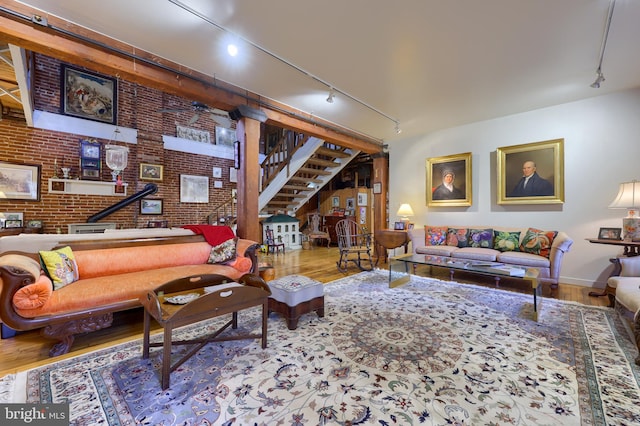 living room featuring brick wall, hardwood / wood-style floors, and track lighting