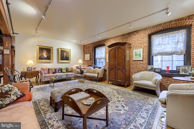 living room featuring rail lighting, brick wall, and hardwood / wood-style floors