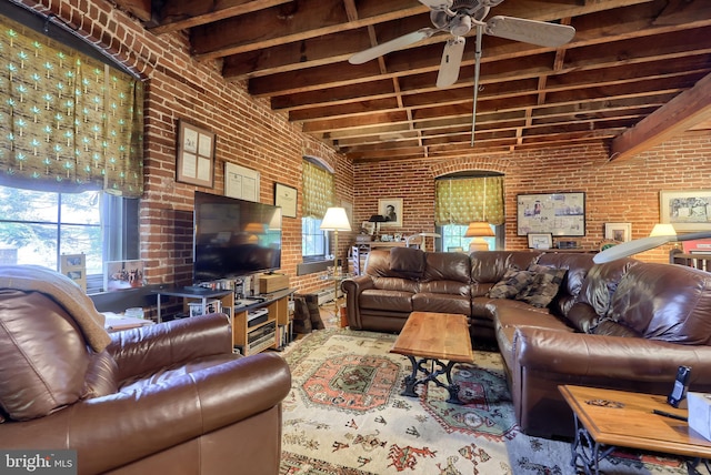 living room with beamed ceiling, ceiling fan, and brick wall