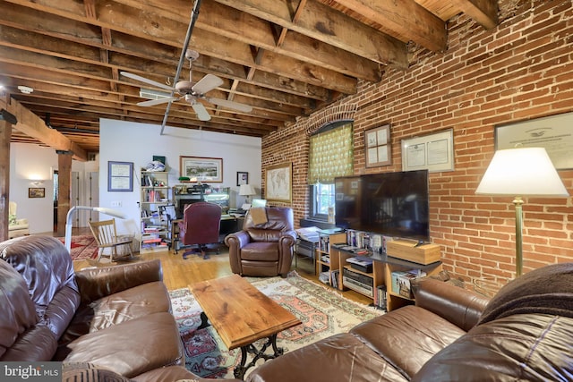 living room with beamed ceiling, ceiling fan, hardwood / wood-style floors, and brick wall