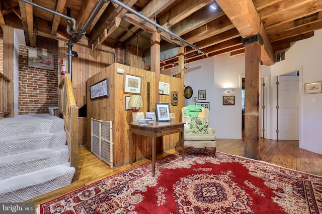 basement featuring wood-type flooring, wooden walls, and brick wall