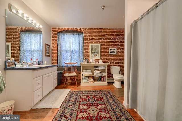 bathroom with brick wall, toilet, vanity, and hardwood / wood-style floors