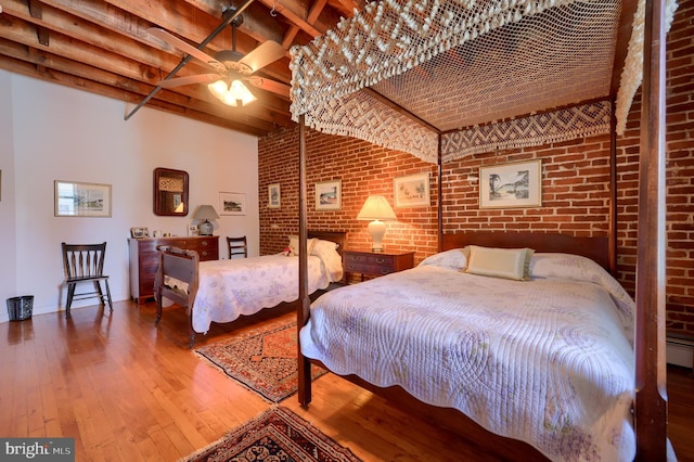 bedroom with beamed ceiling, ceiling fan, hardwood / wood-style floors, and brick wall