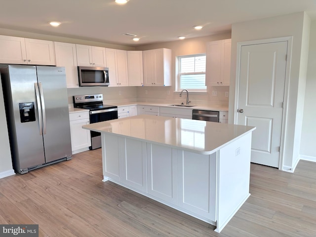 kitchen featuring stainless steel appliances, light hardwood / wood-style flooring, white cabinetry, and a kitchen island