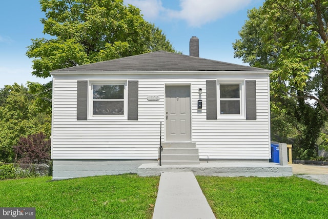 bungalow featuring entry steps, a chimney, and a front yard