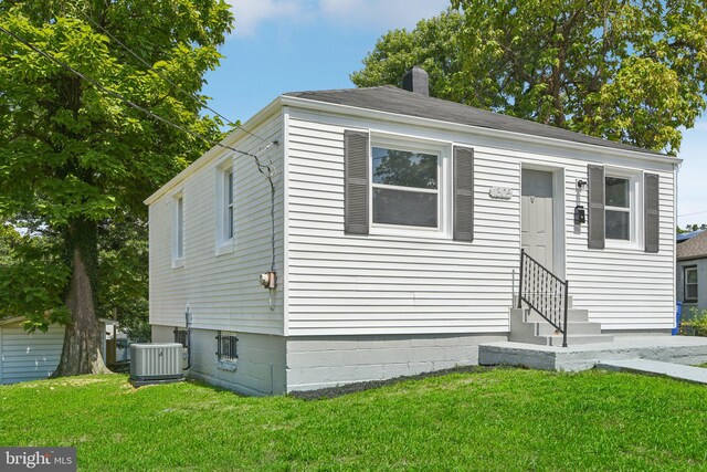 view of front of property featuring a front yard and central AC