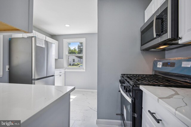 kitchen with stainless steel appliances, white cabinetry, light tile patterned floors, and light stone countertops