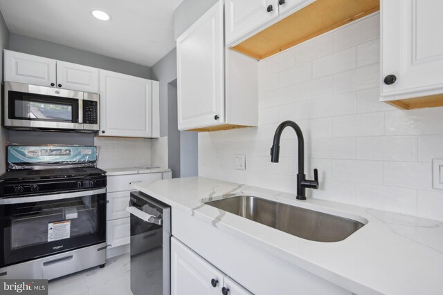 kitchen with white cabinetry, backsplash, appliances with stainless steel finishes, and light tile patterned floors