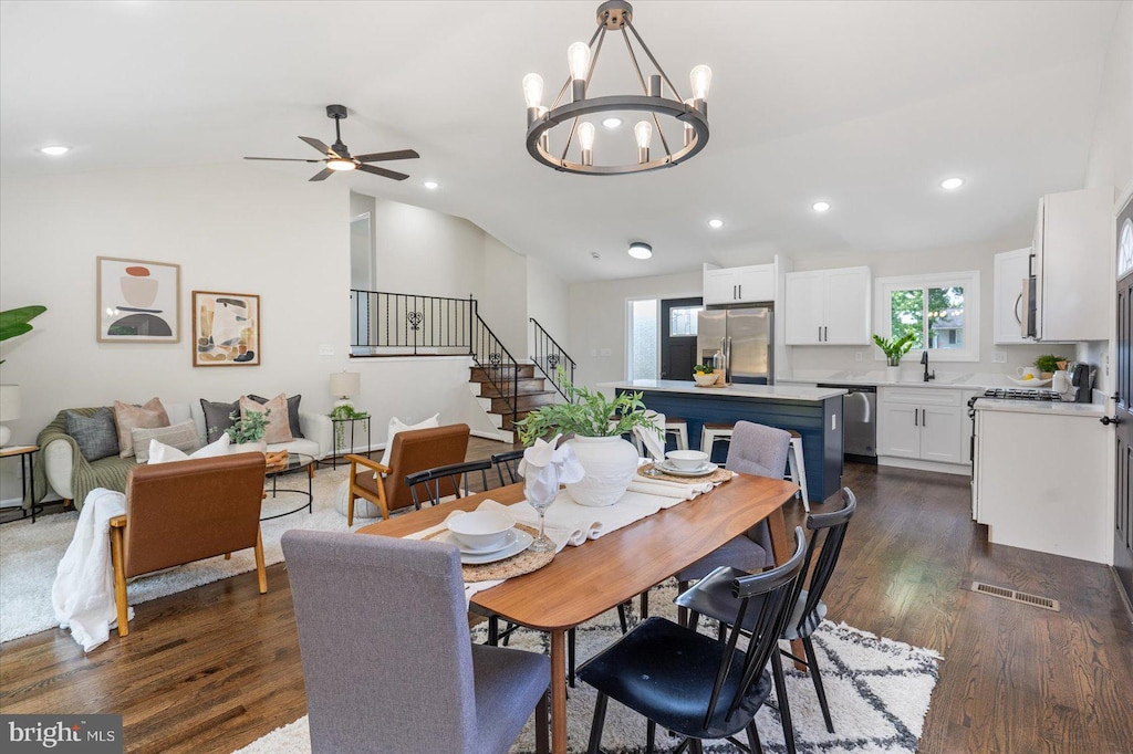 dining space featuring lofted ceiling, ceiling fan with notable chandelier, dark hardwood / wood-style floors, and sink