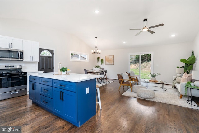 kitchen featuring ceiling fan with notable chandelier, blue cabinets, appliances with stainless steel finishes, a center island, and lofted ceiling