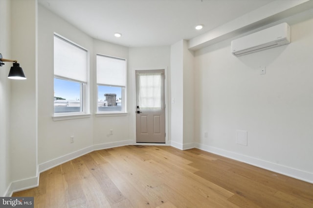 interior space with a wall mounted air conditioner and light hardwood / wood-style floors