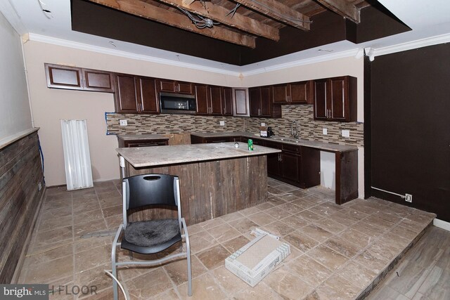 kitchen featuring crown molding, a center island, sink, and decorative backsplash