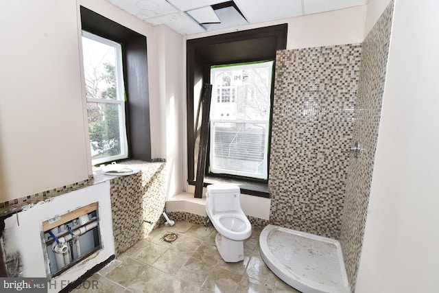 bathroom featuring tiled shower and toilet