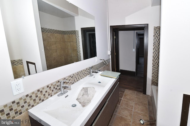 bathroom with tasteful backsplash, wood-type flooring, dual bowl vanity, and lofted ceiling