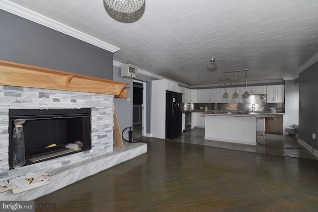 unfurnished living room featuring crown molding, a stone fireplace, dark wood-type flooring, and sink