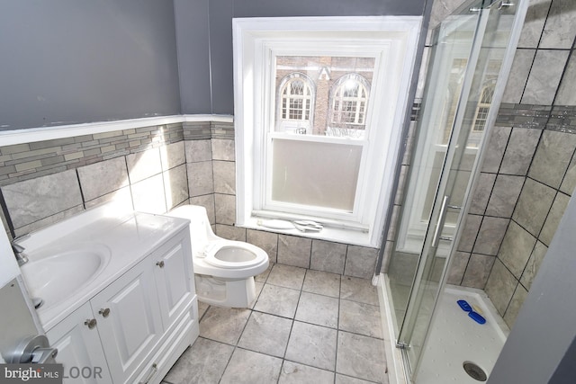 bathroom featuring tile walls, tile patterned flooring, vanity, toilet, and a shower with door