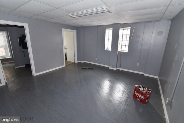 spare room featuring a drop ceiling, wood-type flooring, and plenty of natural light