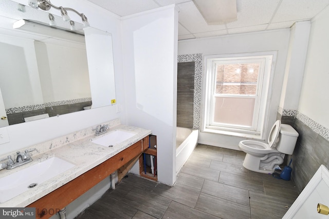 bathroom with vanity, a paneled ceiling, tile walls, and toilet