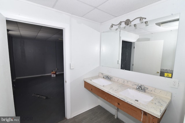 bathroom featuring double vanity, a paneled ceiling, and wood-type flooring