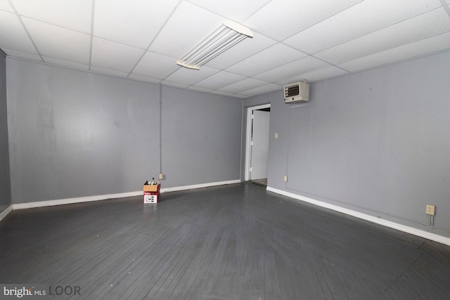 spare room featuring dark wood-type flooring and a paneled ceiling