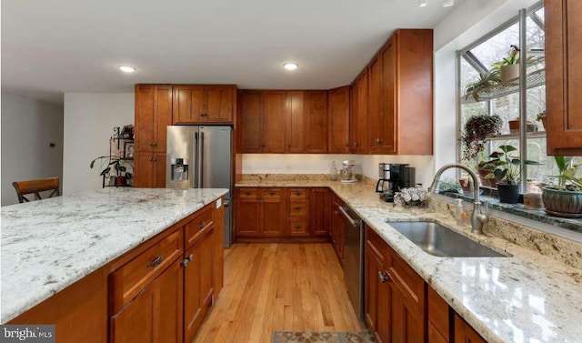 kitchen featuring light stone countertops, sink, stainless steel appliances, and light hardwood / wood-style flooring