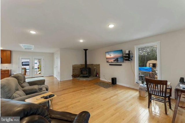 living room featuring french doors, a wood stove, and light wood-type flooring