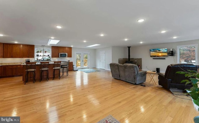 living room with french doors, a wood stove, and light wood-type flooring