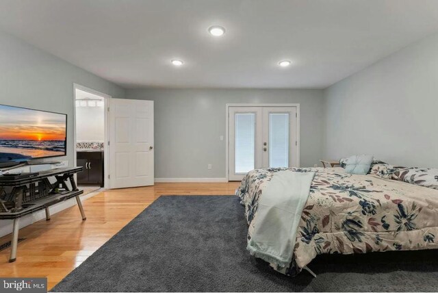 bedroom featuring ensuite bath, light hardwood / wood-style flooring, french doors, and multiple windows