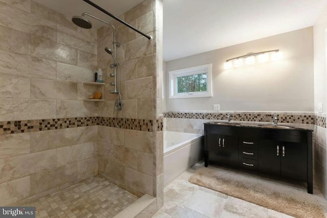 bathroom with shower with separate bathtub, dual bowl vanity, tile walls, and tile patterned floors