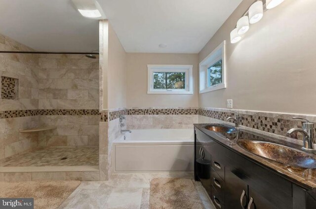 bathroom with double sink vanity, tasteful backsplash, tile patterned floors, and separate shower and tub