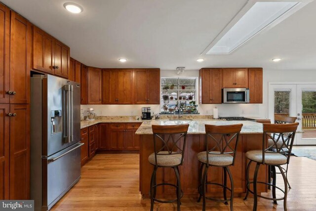 kitchen featuring appliances with stainless steel finishes, a breakfast bar, a wealth of natural light, and light hardwood / wood-style floors