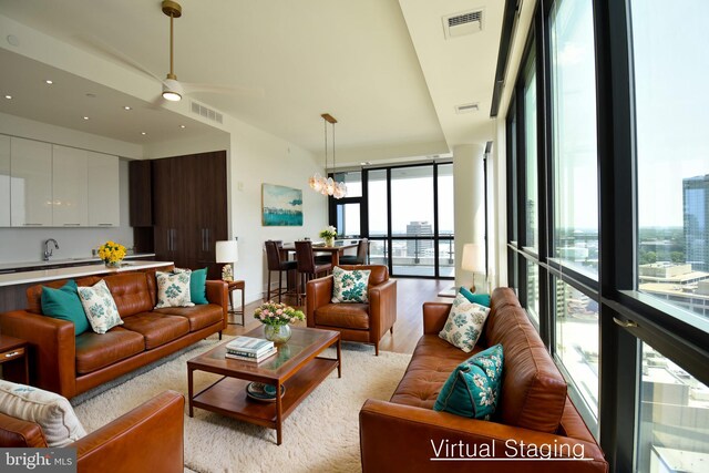 living room with ceiling fan with notable chandelier, floor to ceiling windows, and light hardwood / wood-style floors