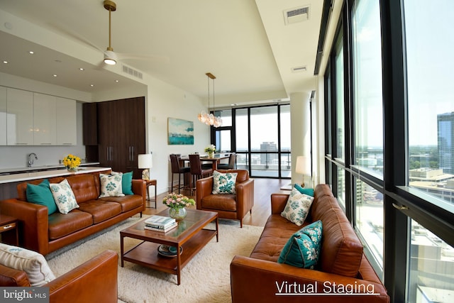 living room with a wall of windows, light hardwood / wood-style floors, and a chandelier