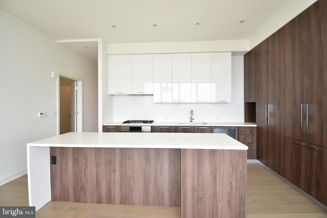 kitchen with a center island, sink, white cabinets, and light hardwood / wood-style floors