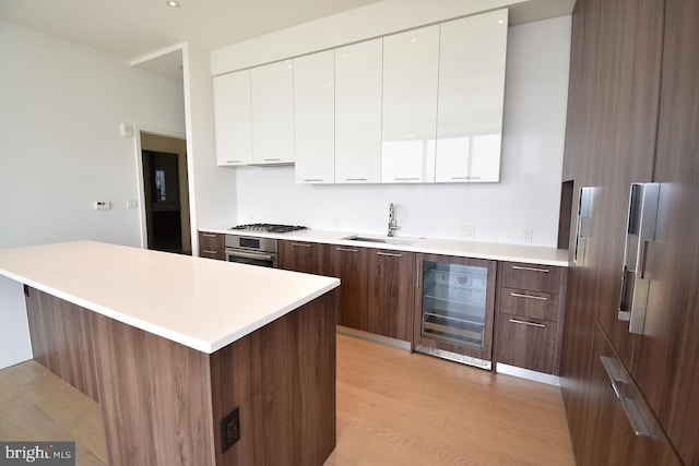 kitchen featuring white cabinetry, appliances with stainless steel finishes, beverage cooler, and sink