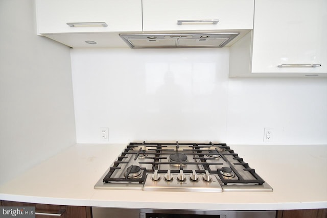 kitchen featuring stainless steel gas stovetop, extractor fan, and white cabinets