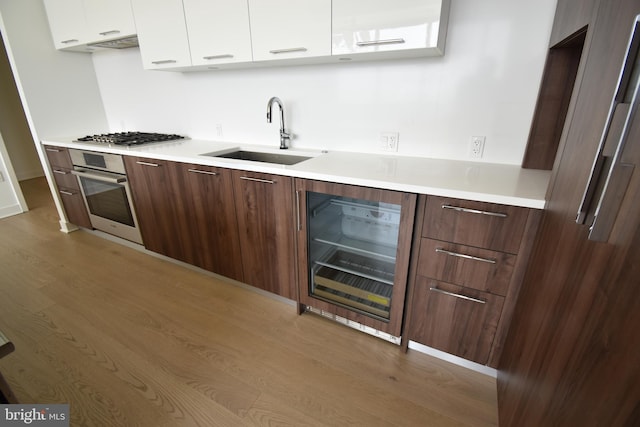 kitchen featuring sink, stainless steel appliances, beverage cooler, and white cabinets