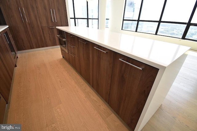 kitchen with dark brown cabinets, light hardwood / wood-style flooring, and oven