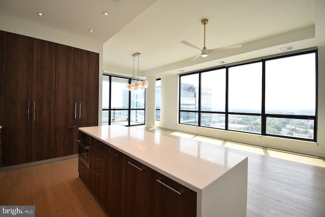 kitchen featuring pendant lighting, a center island, light hardwood / wood-style floors, ceiling fan with notable chandelier, and oven