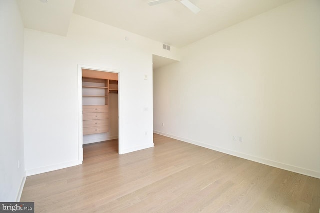 unfurnished bedroom featuring a walk in closet, a closet, and light wood-type flooring