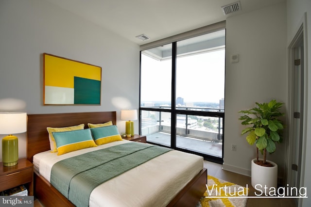 bedroom featuring expansive windows, wood-type flooring, and access to exterior