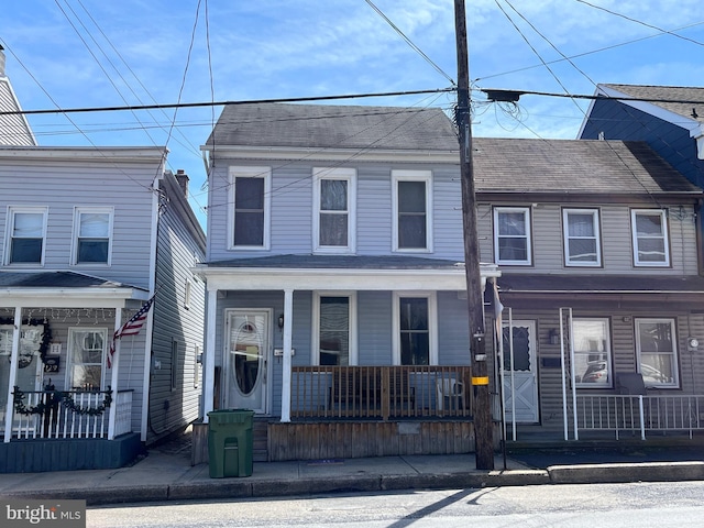 view of property with covered porch and roof with shingles